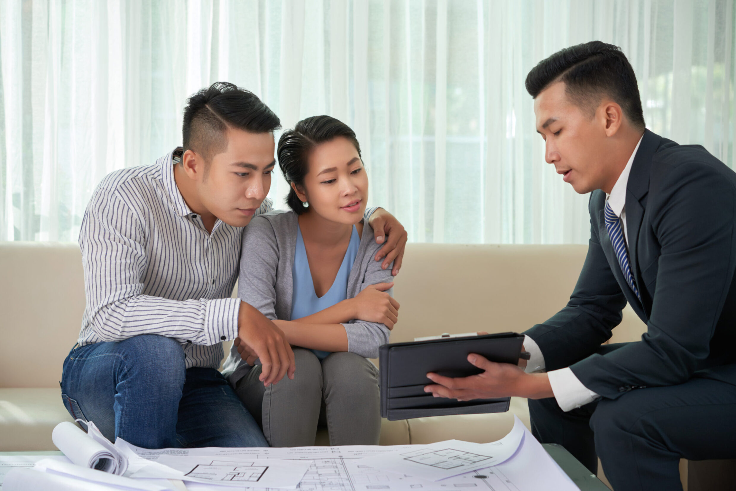 Broker showing real estate object Real estate broker showing photos of house on digital tablet to young couple