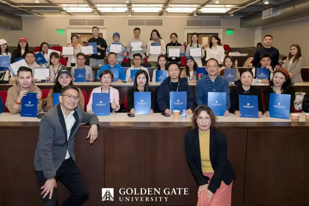 GGU 主校門口 2026 年 5 月學員大合照,GGU 入口拱門 + Your mission is our mission 旗幟